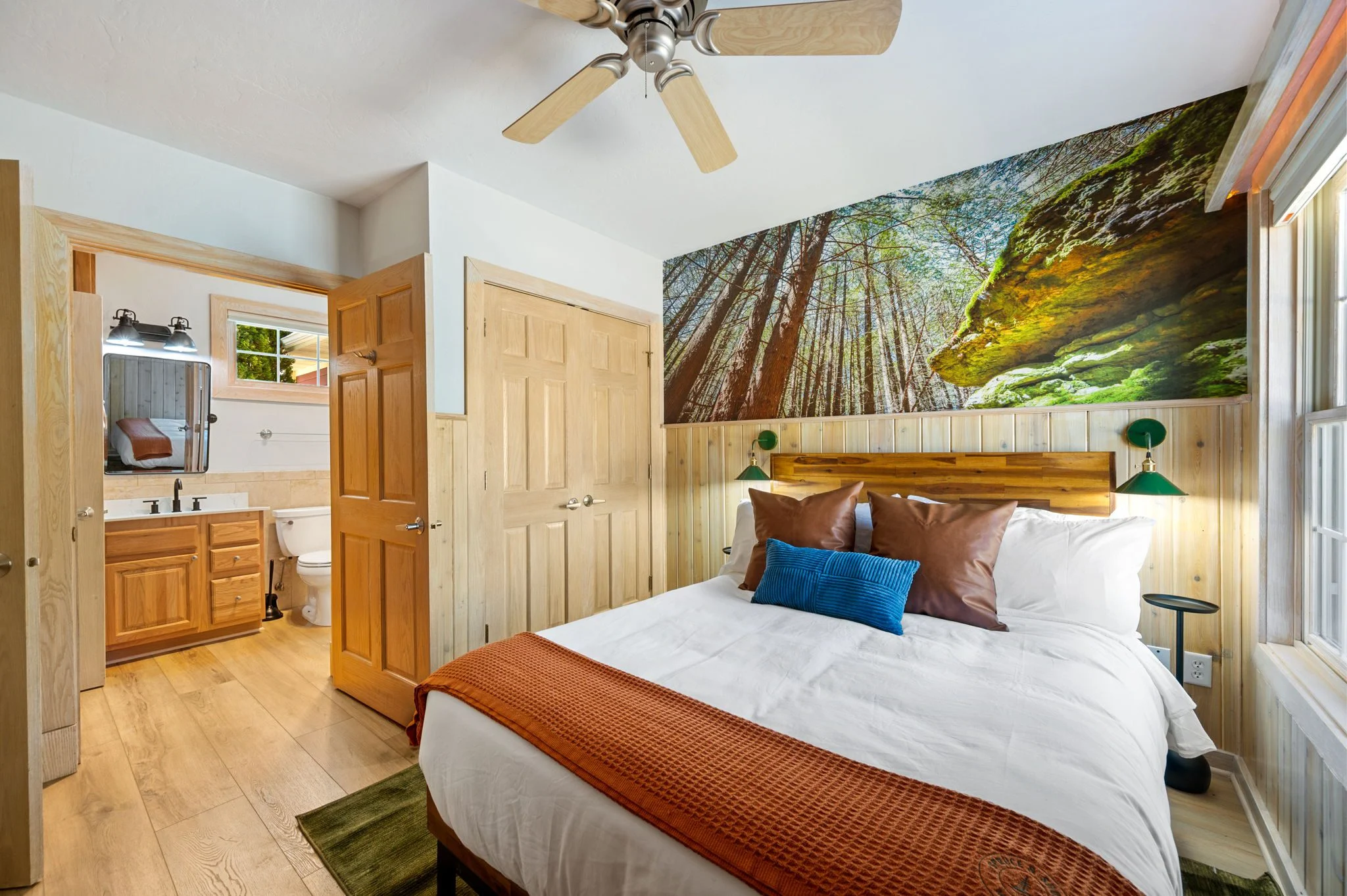 Cozy bedroom with forest mural and en suite bathroom.