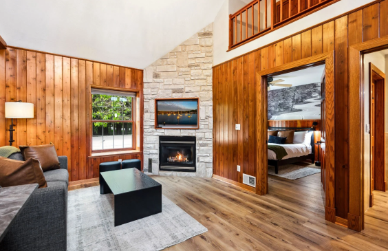 Cozy cabin living room with fireplace and bedroom view.